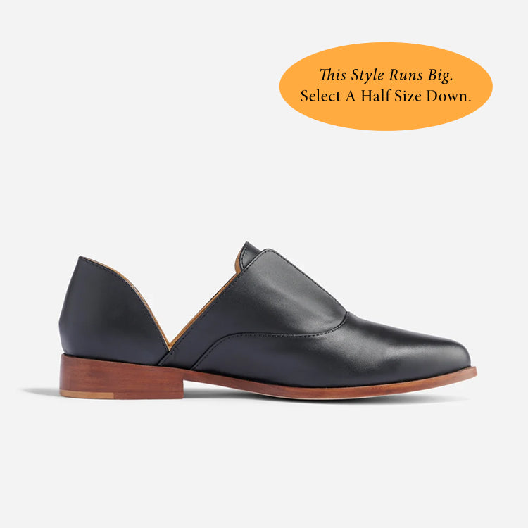 Single black leather d'Orsay Oxford shoe with a brown wood-look heel and side cutouts on a white background.
